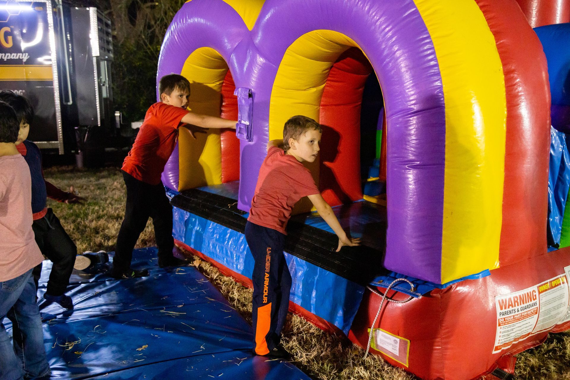 Kids climb into a bounce house.