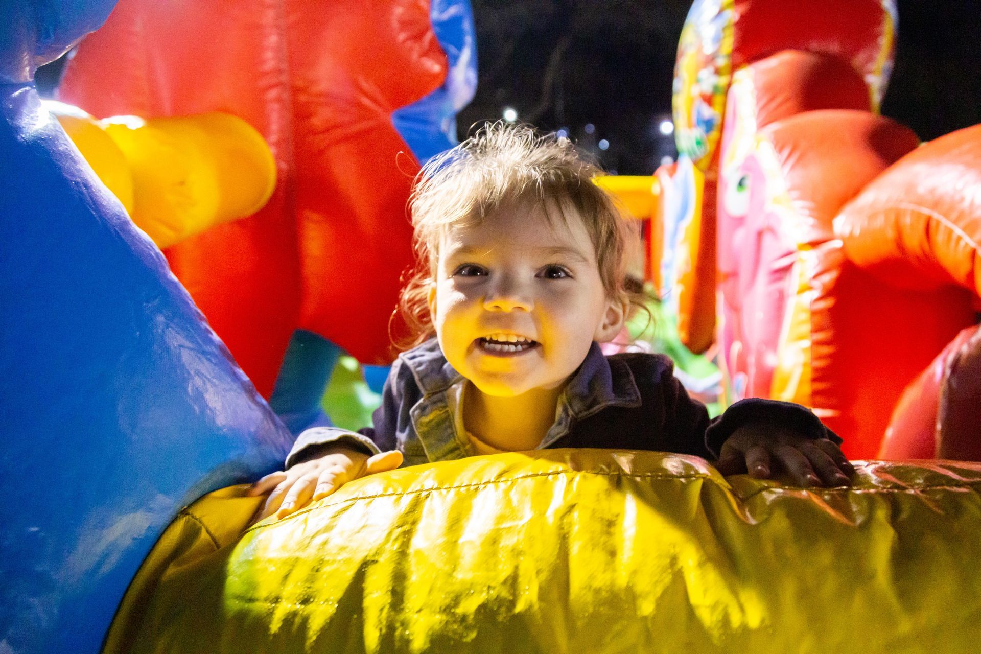 A little toddler is playing in a bounce house at the ICL Fall Family picnic.