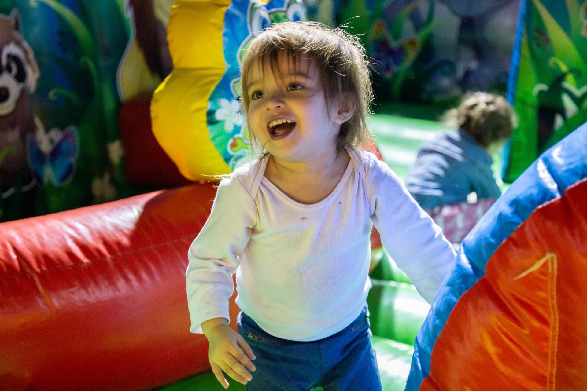 Cute little toddler is laughing in a bounce house.
