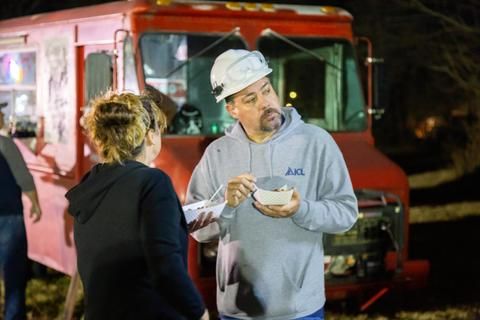 A man stands and eats his food at the family picnic for ICL.