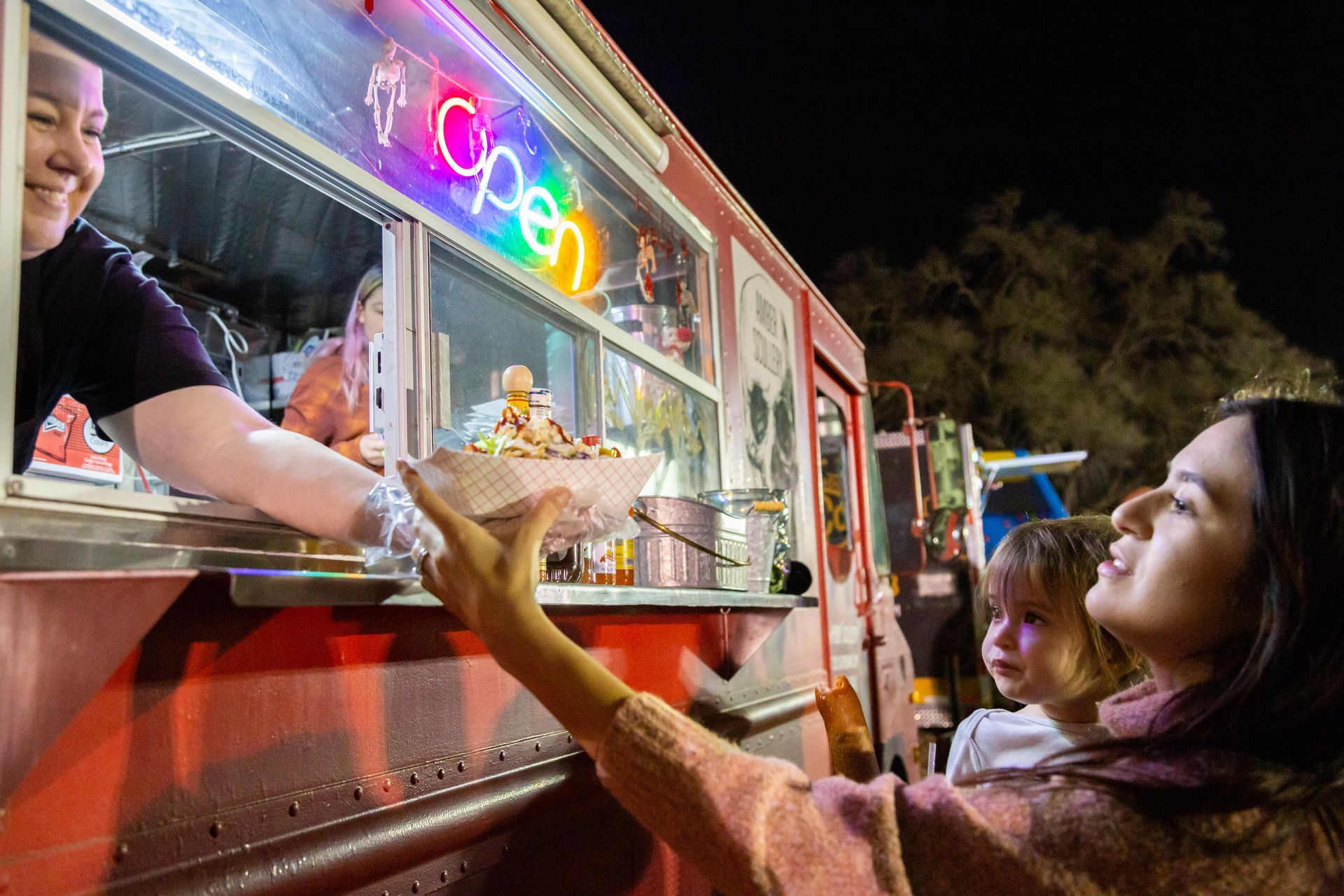 A woman receives a paper bowl of food from the food truck.