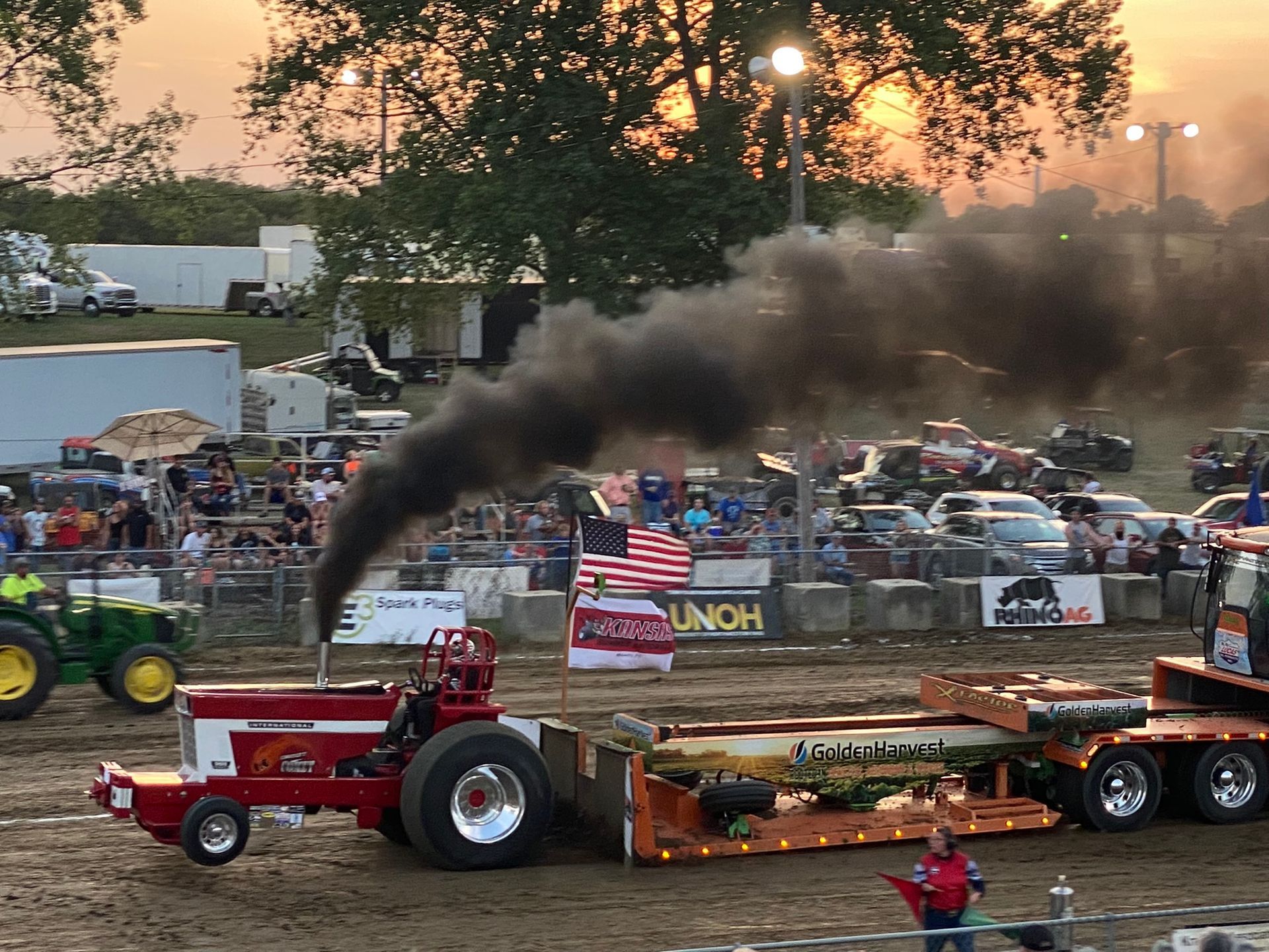Smoke rises from a tractor with lots of cars around it.