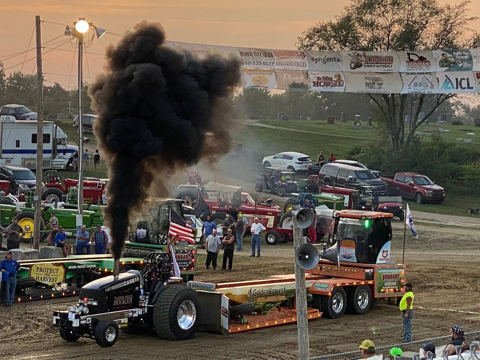 Smoke rises from a tractor with lots of cars around it.