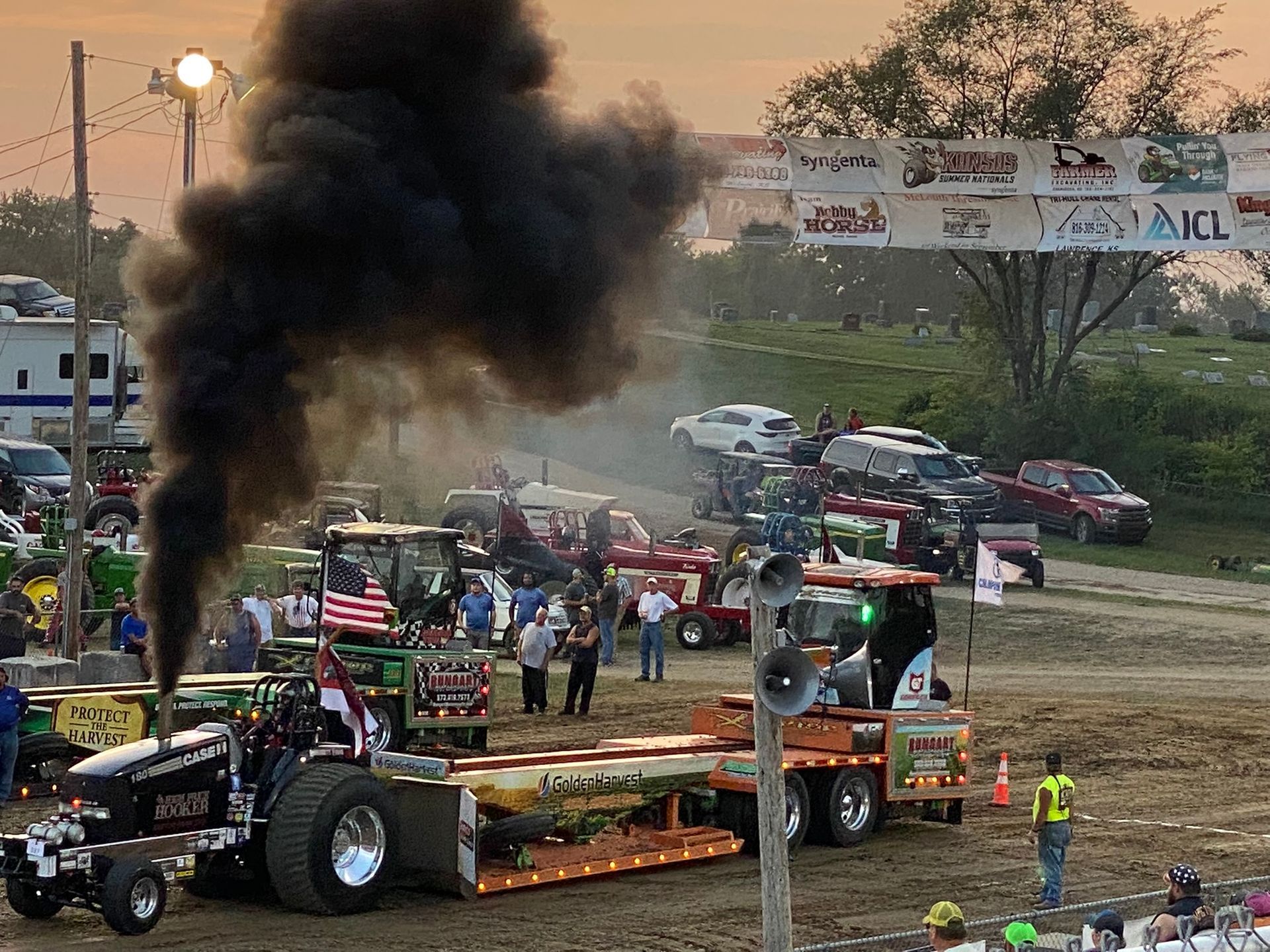 Smoke rises from a tractor with lots of cars around it.