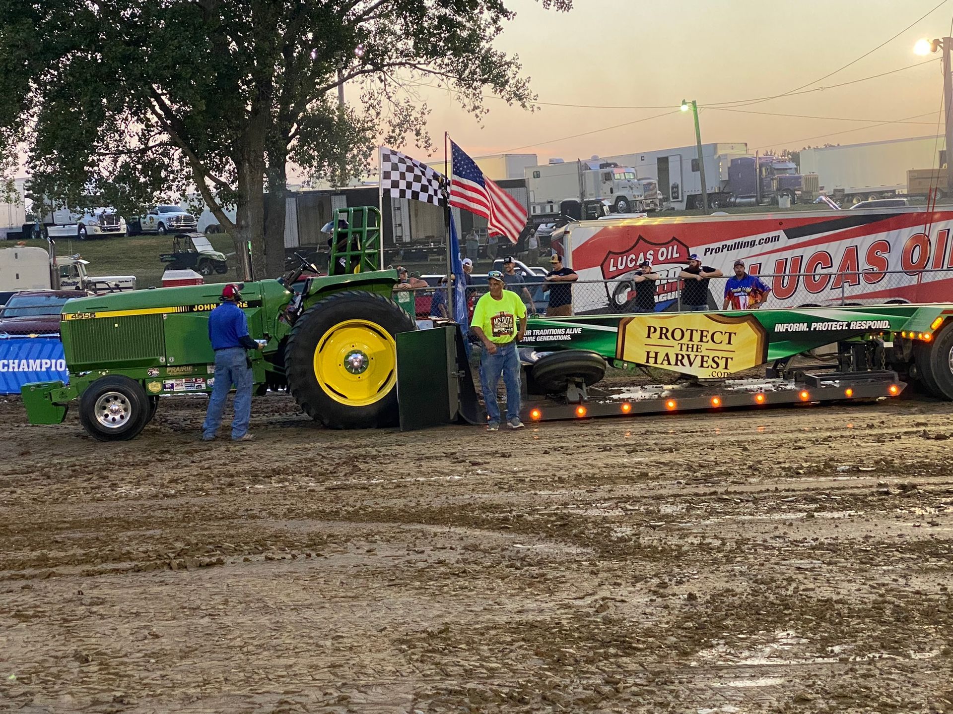 Men are standing next to a large tractor.