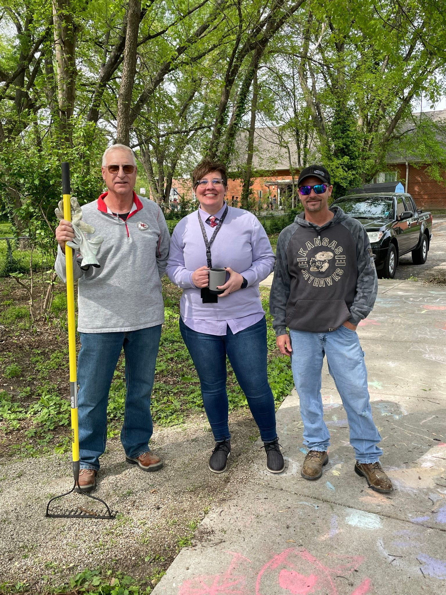 Three ICL employees smiling at the camera at the community gardern.