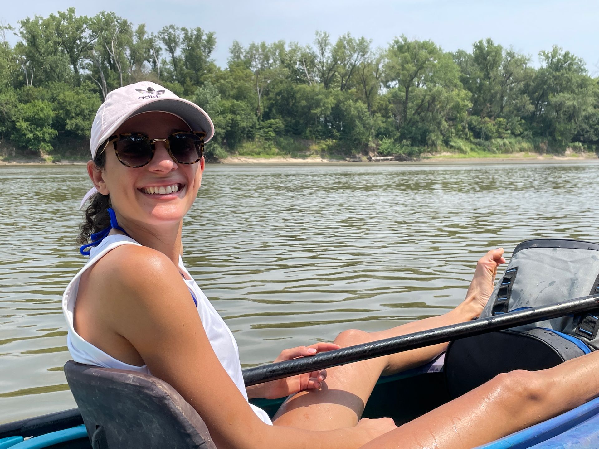 A moan is sitting in her boat and floating down the river. She is smiling.