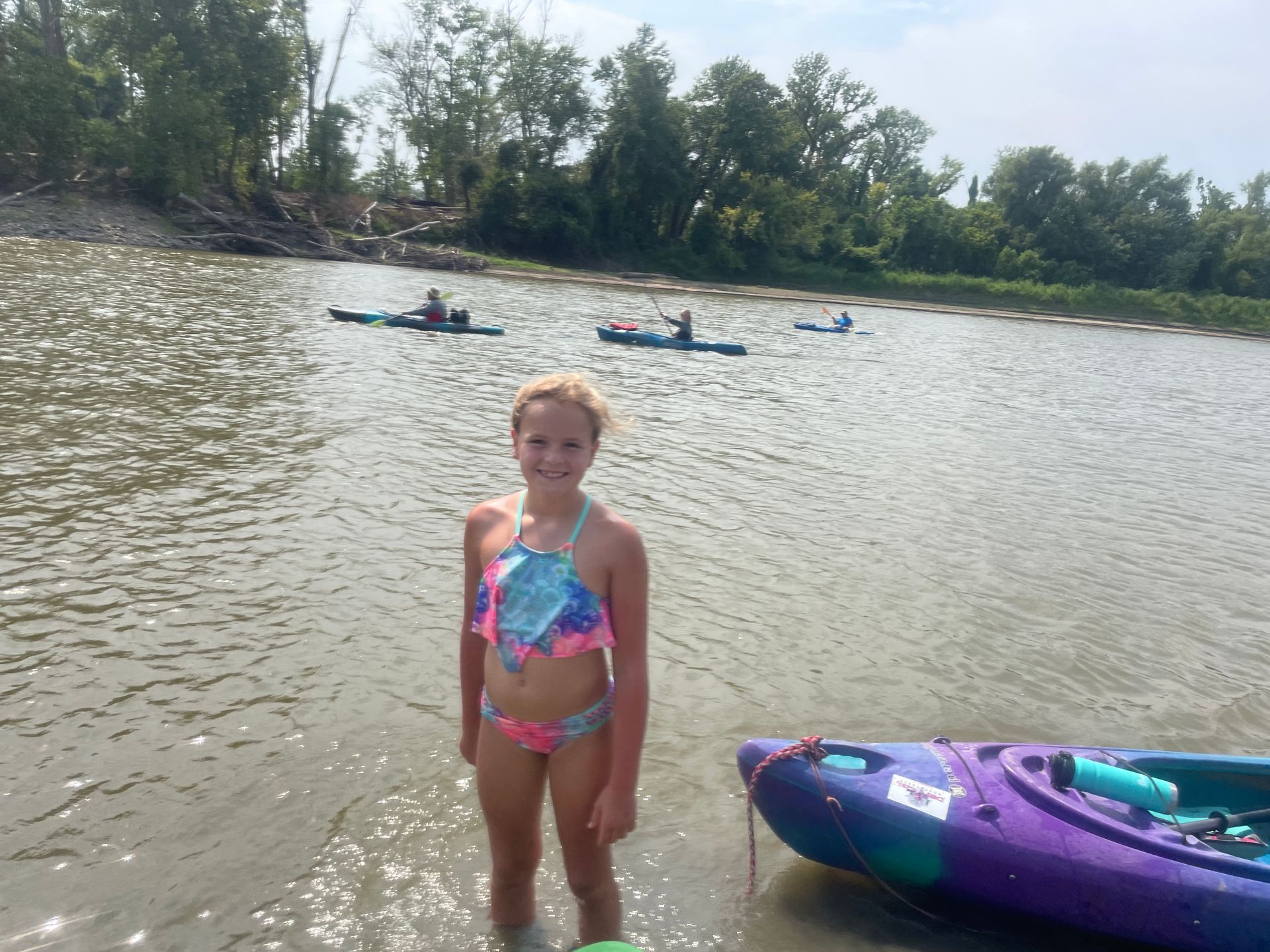 A young girl is standing in the river and getting ready to get in her canoe.
