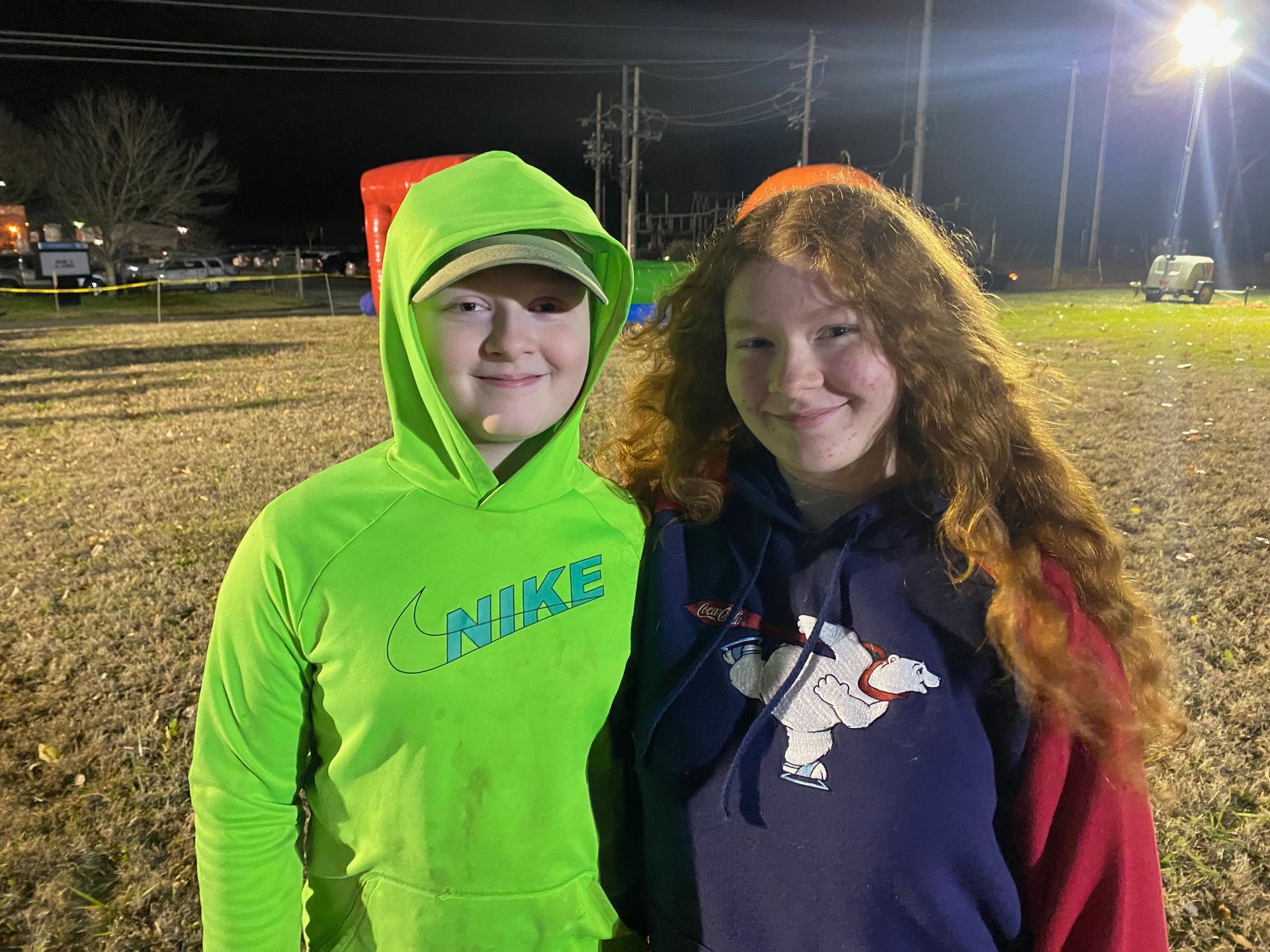 A boy and a girl are posing for a picture in a field at night.