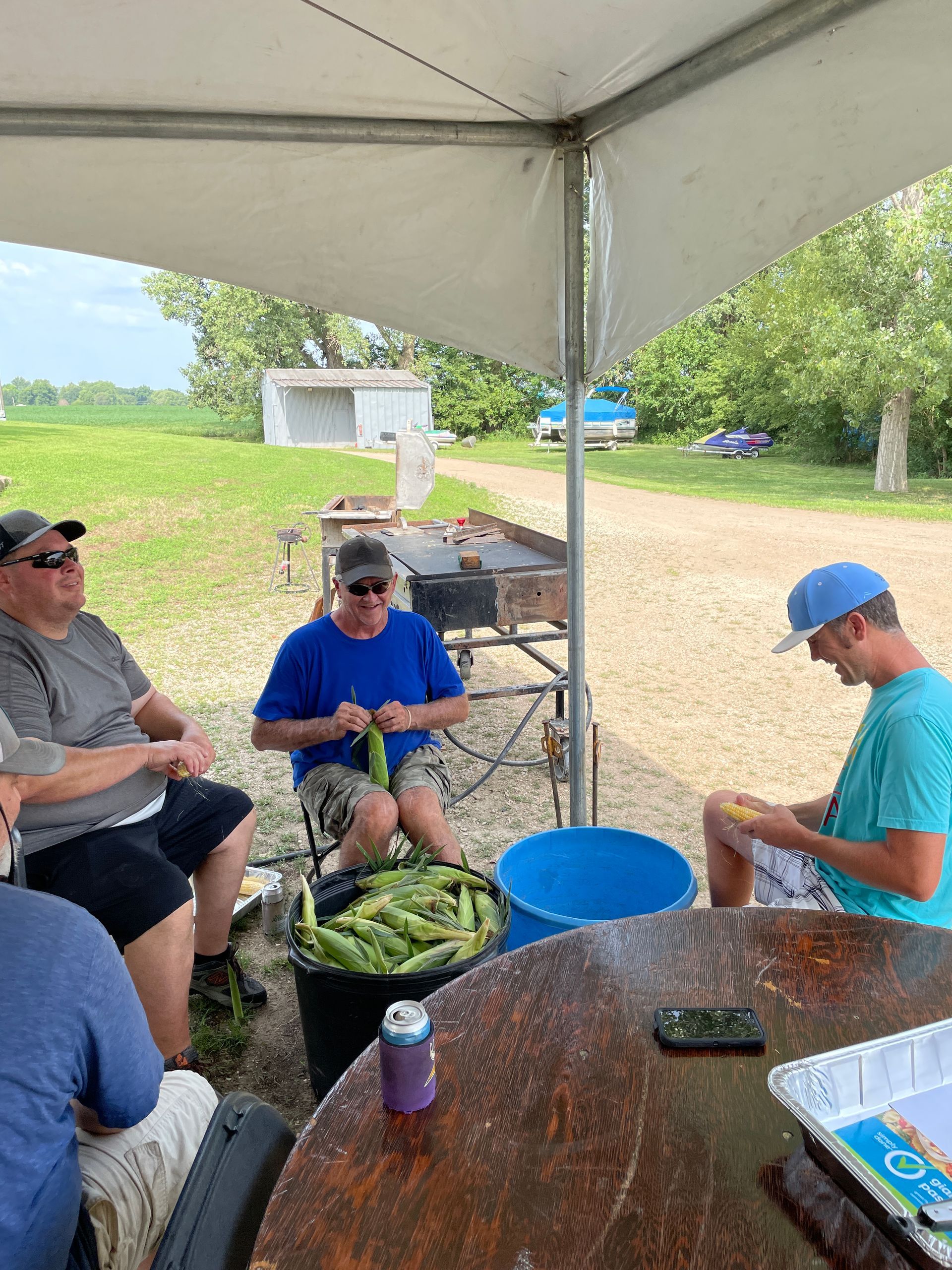 a group of icl employees are sitting around a table under a tent .