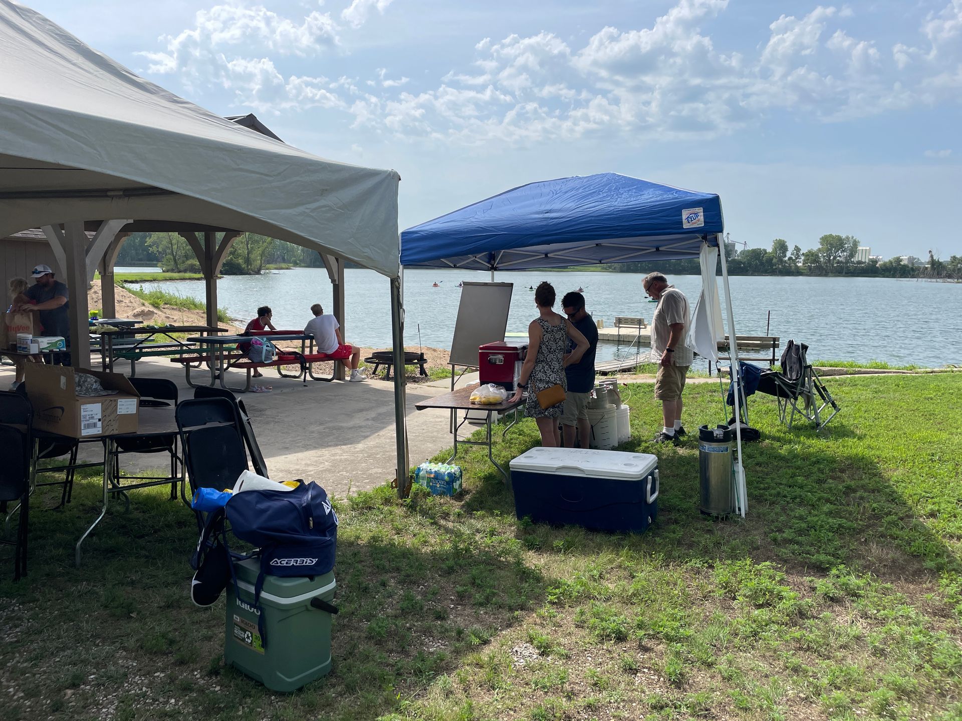 A white tent and a blue tent are positioned in front of the water at the ICL Family Picnic.