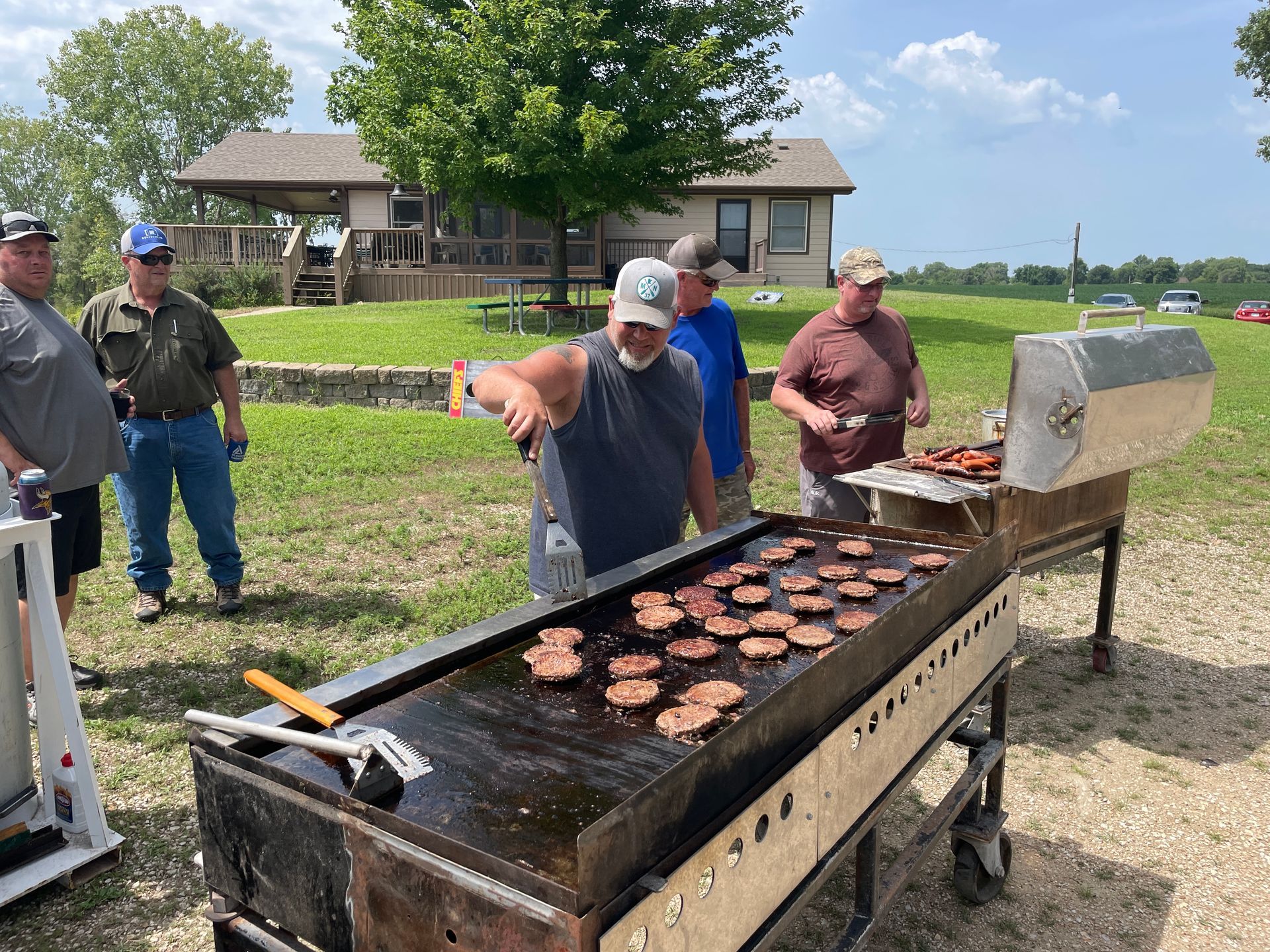 A man is grilling burgers at the ICL Family Picnic.
