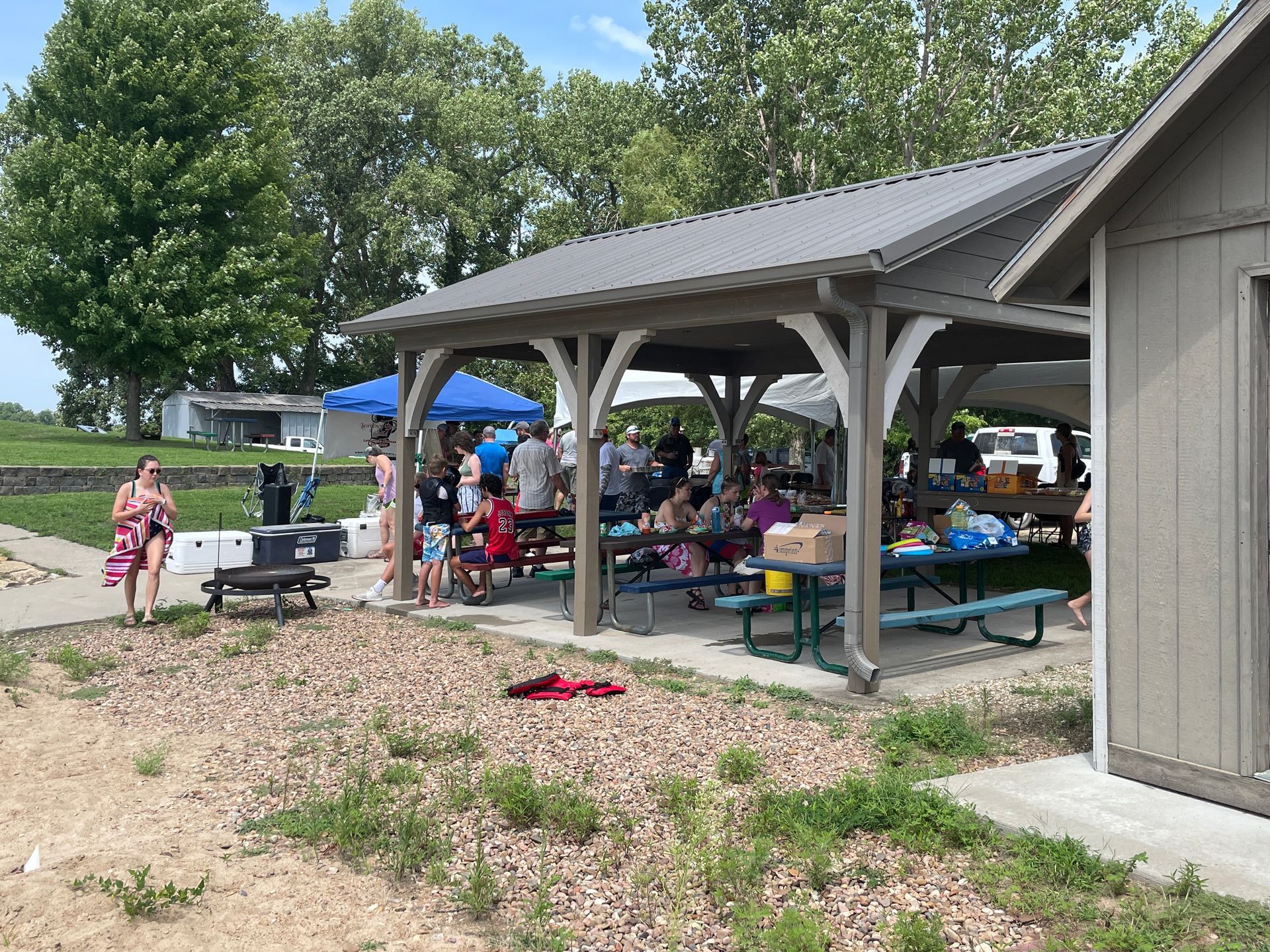 People are gathered under a covered pation at the Family Picnic.