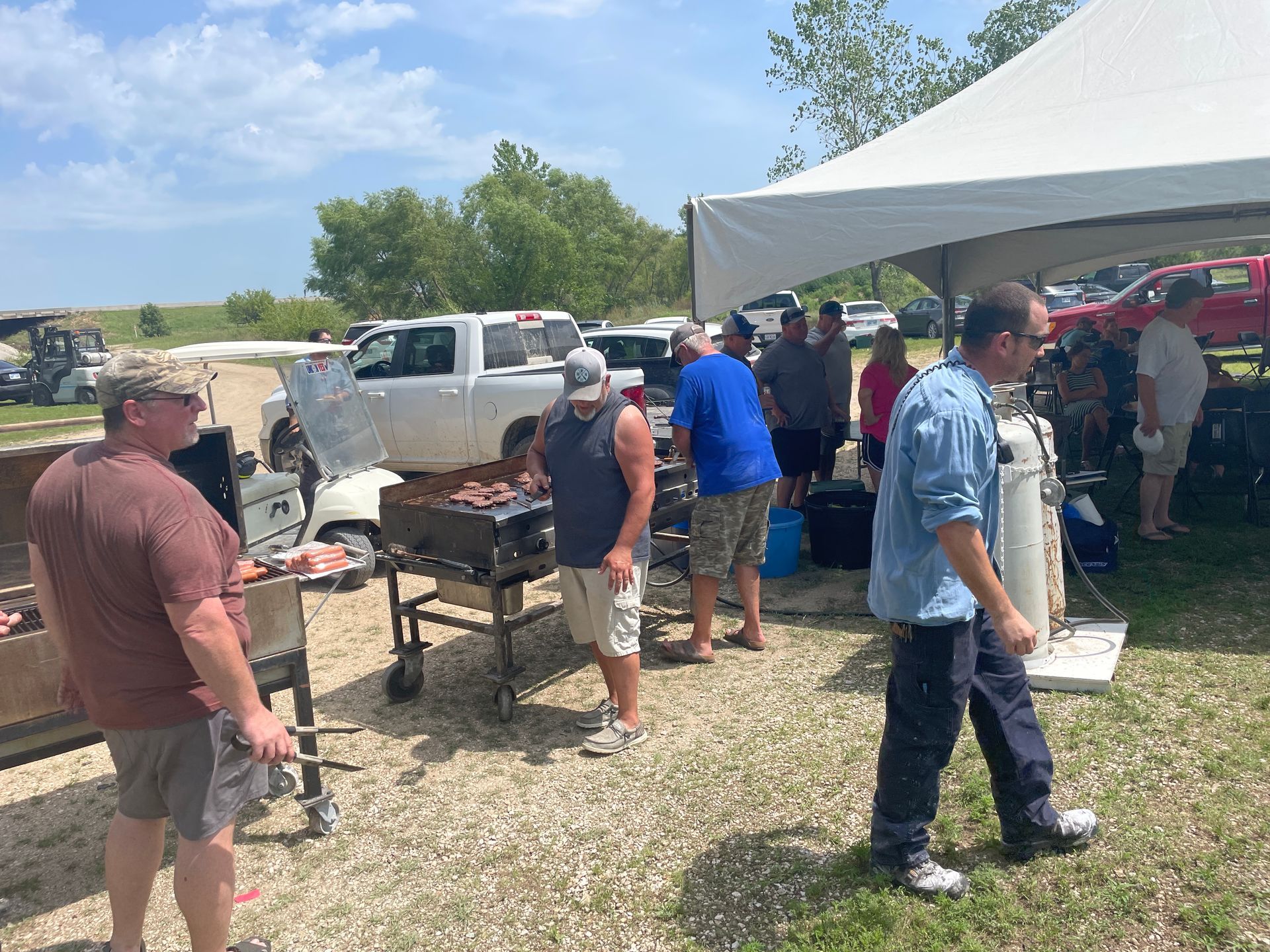 Adults are standing near a white tent. 
