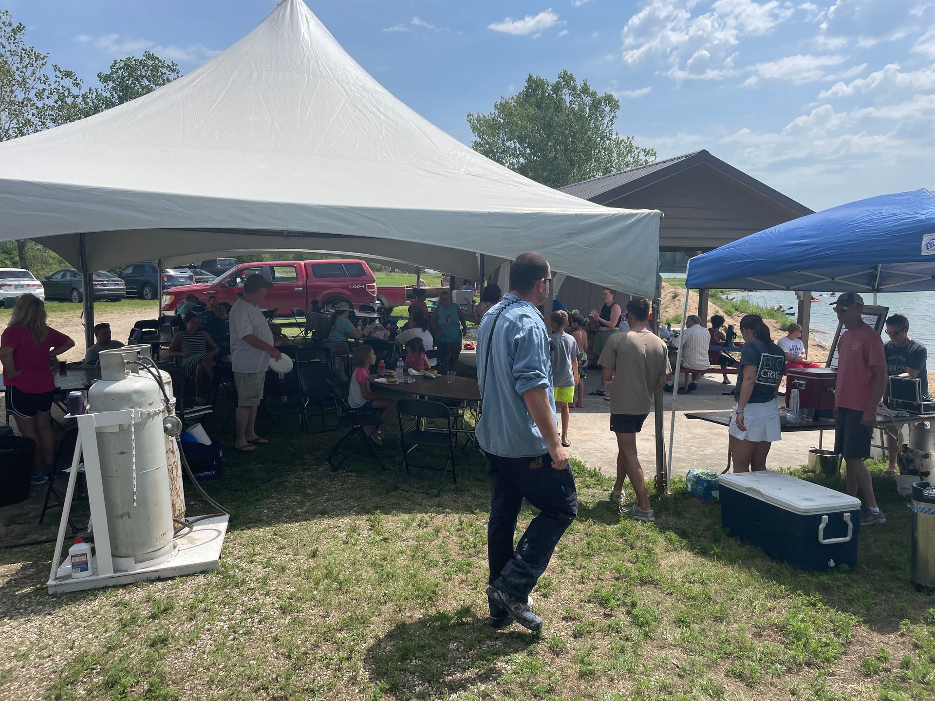 Adults are sitting at a table under a large white tent.