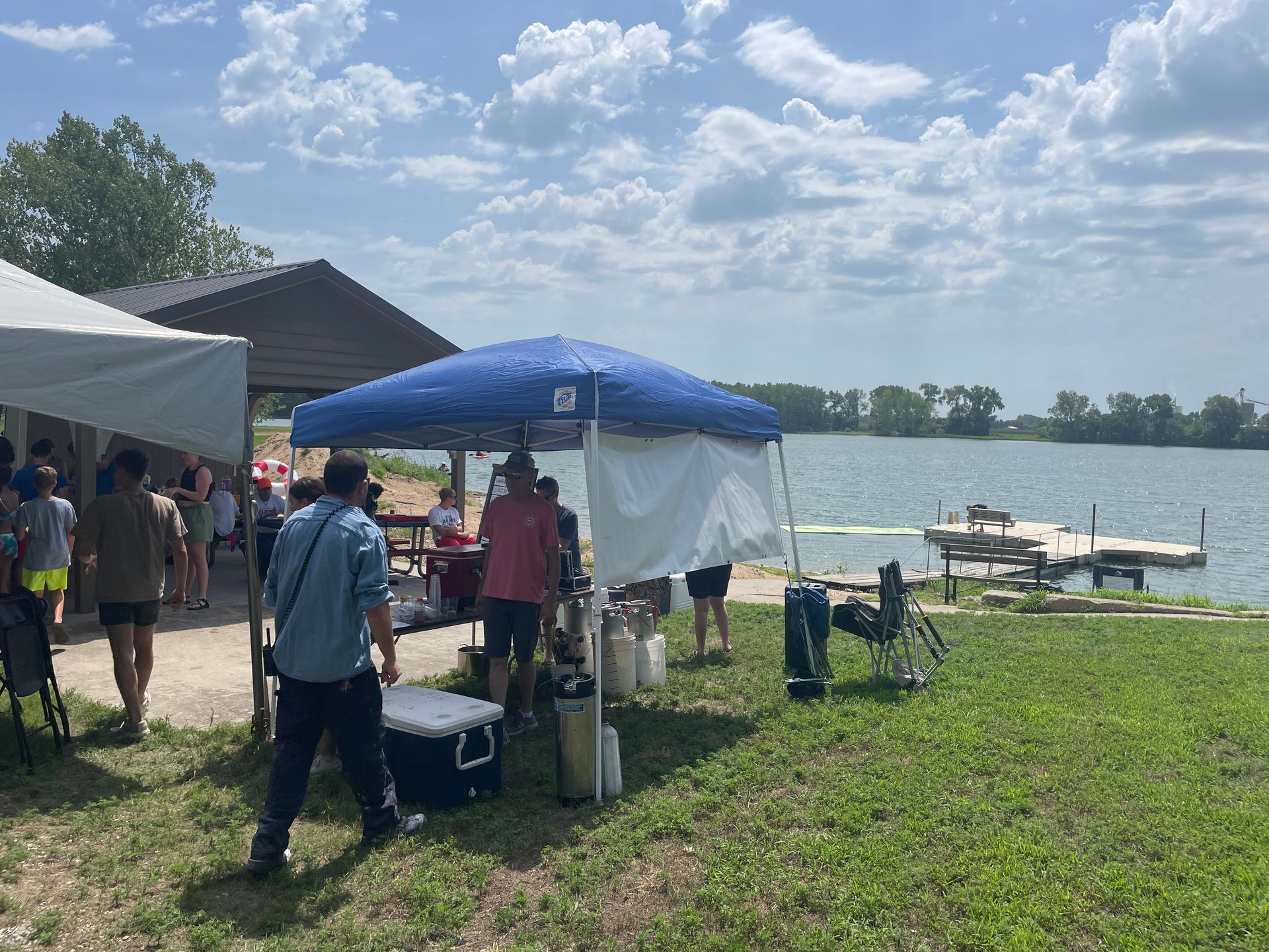 A small blue tent stands in from of a lake.