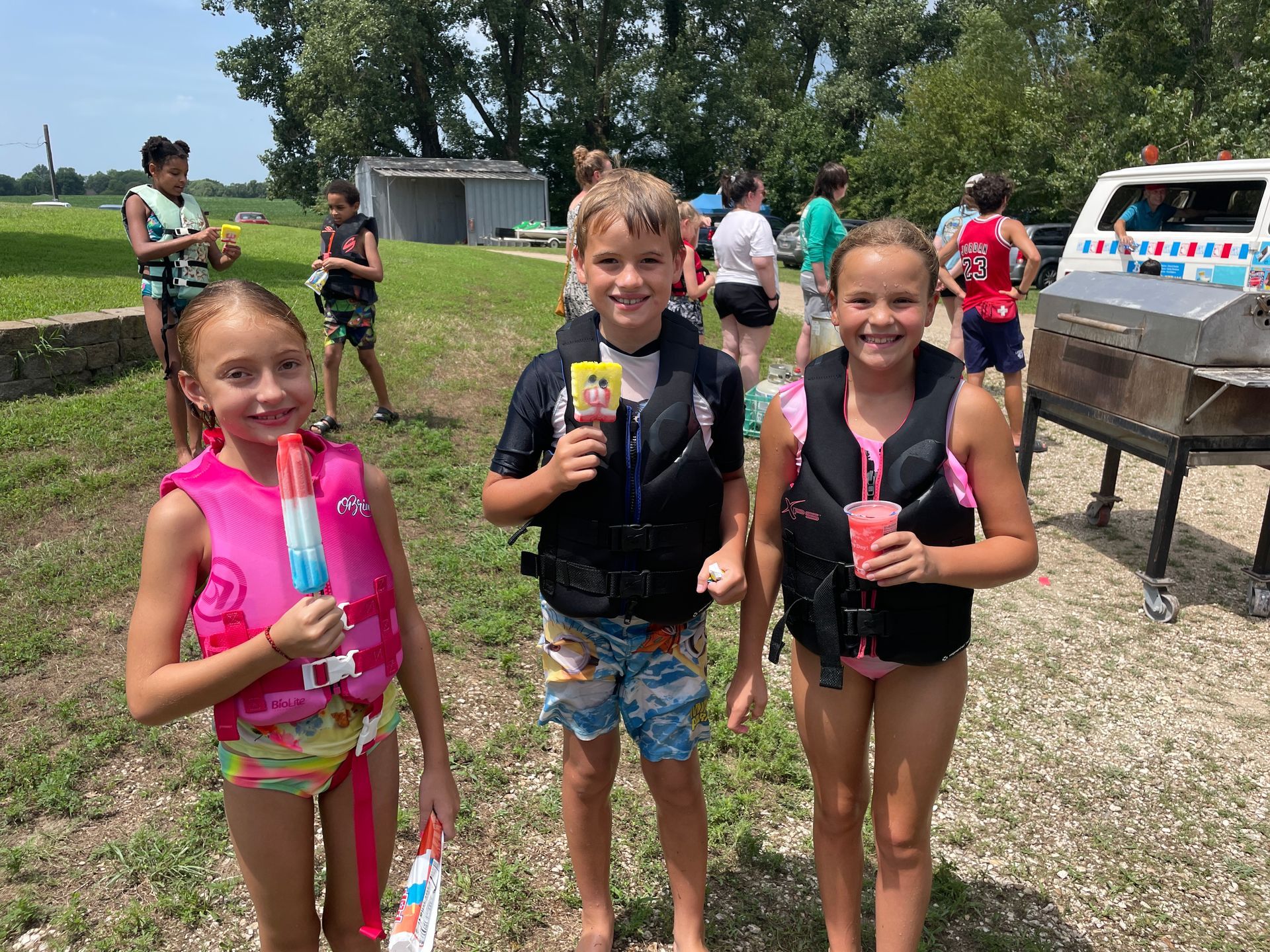 Cute kids are in their swimsuits and eating pop sicles.