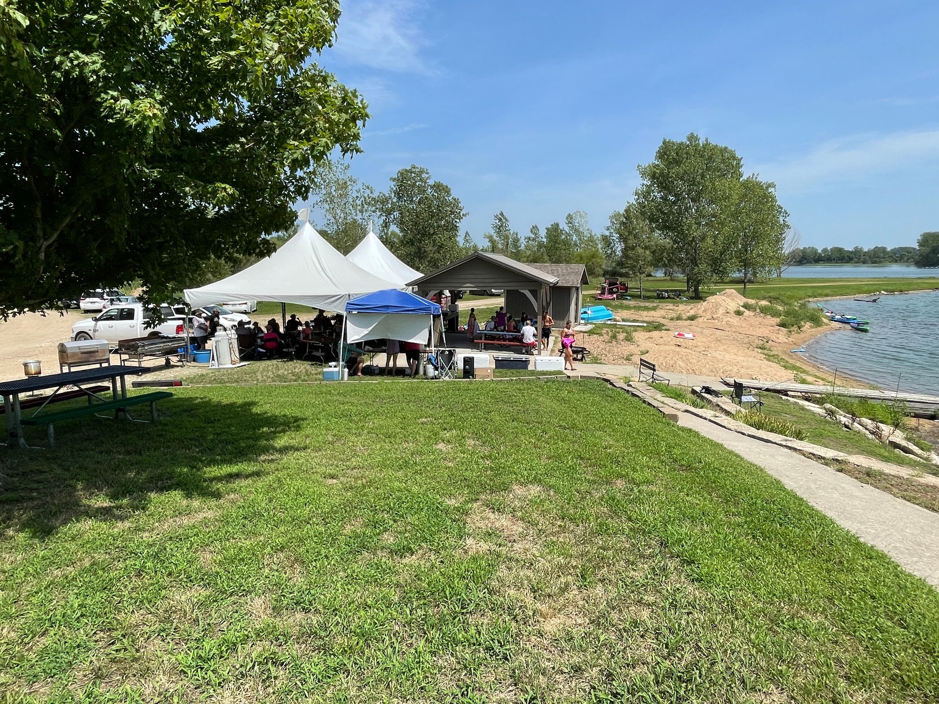 Adults are sitting at a table under a large white tent.