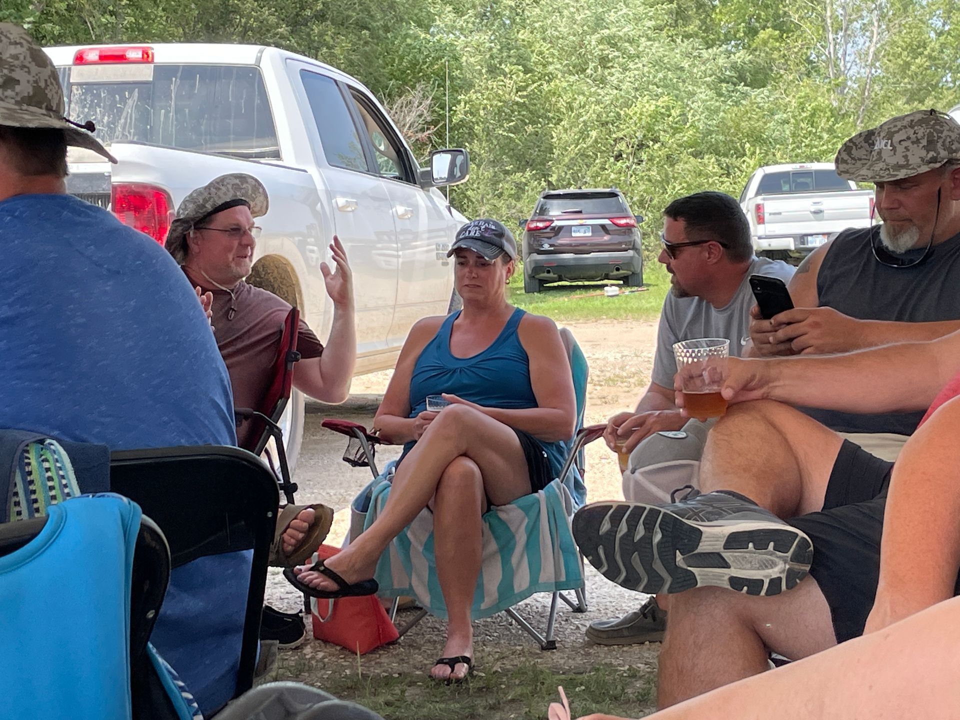 Adults are sitting at a table under a large white tent.