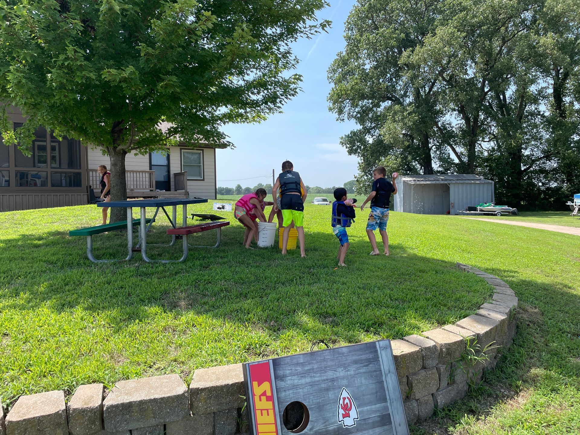 Kids are playing on the lawn and are pulling something from a bucket.
