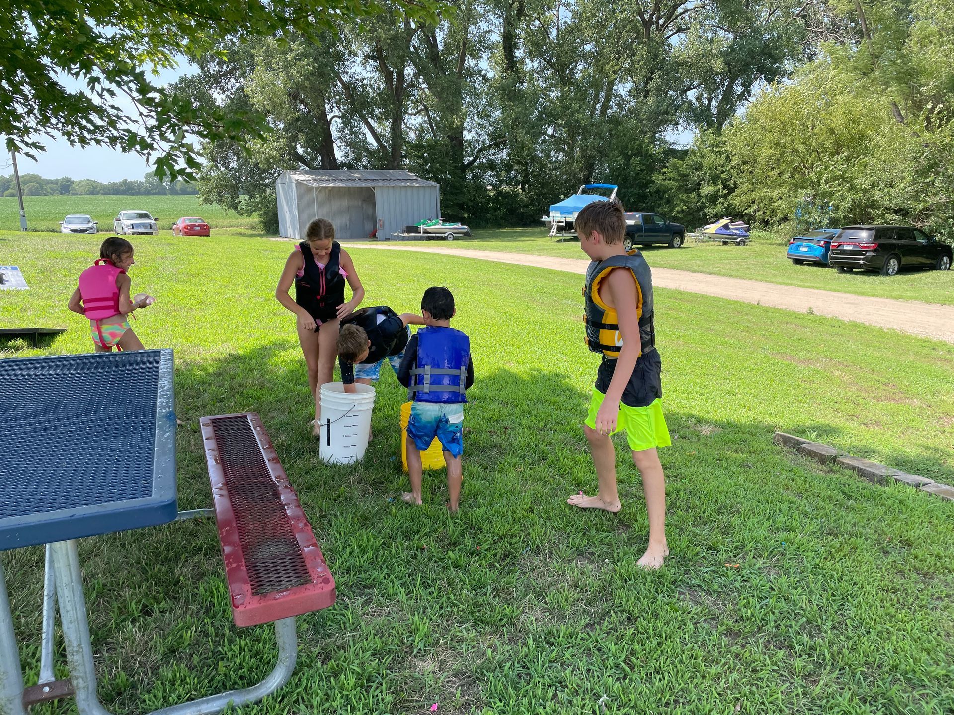 Kids are in their swim suits and they are playing in the grass.