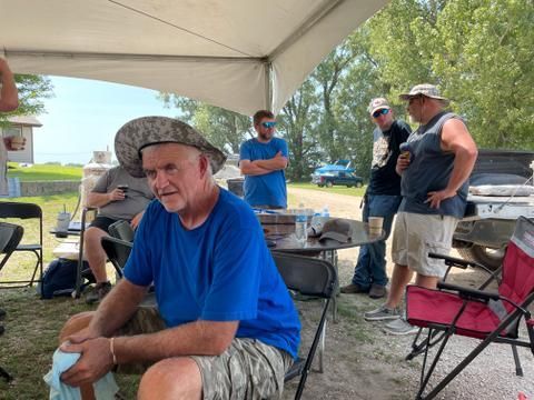 People are sitting under a tent during the Summer Picnic.