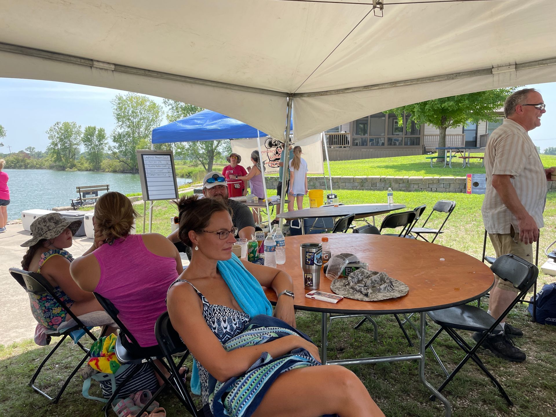 People are sitting at tables under the big white tents.