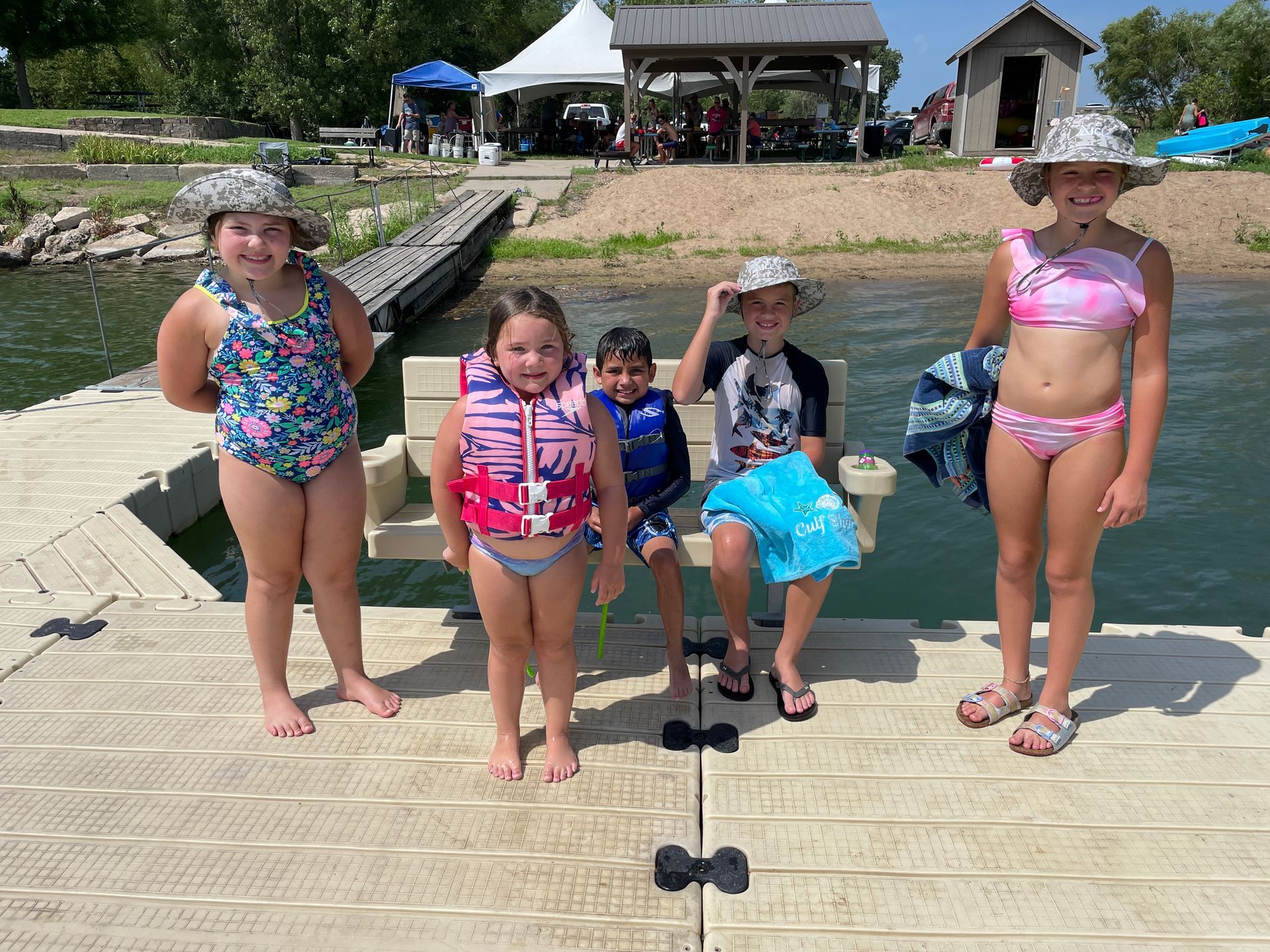 Group of small kids are in their swim suits and smiling at the camera.