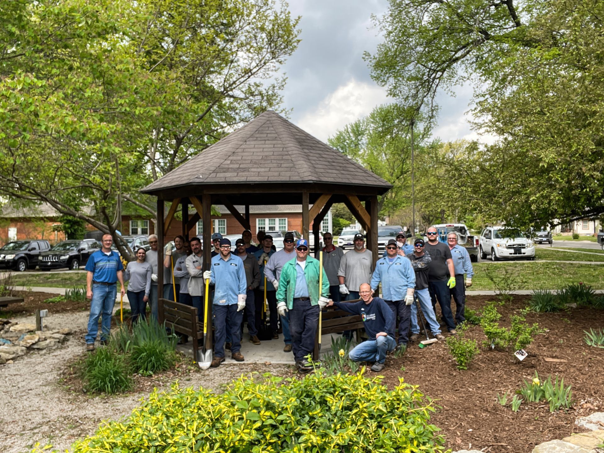a group of icl employees are standing in front of a gazebo in a park .