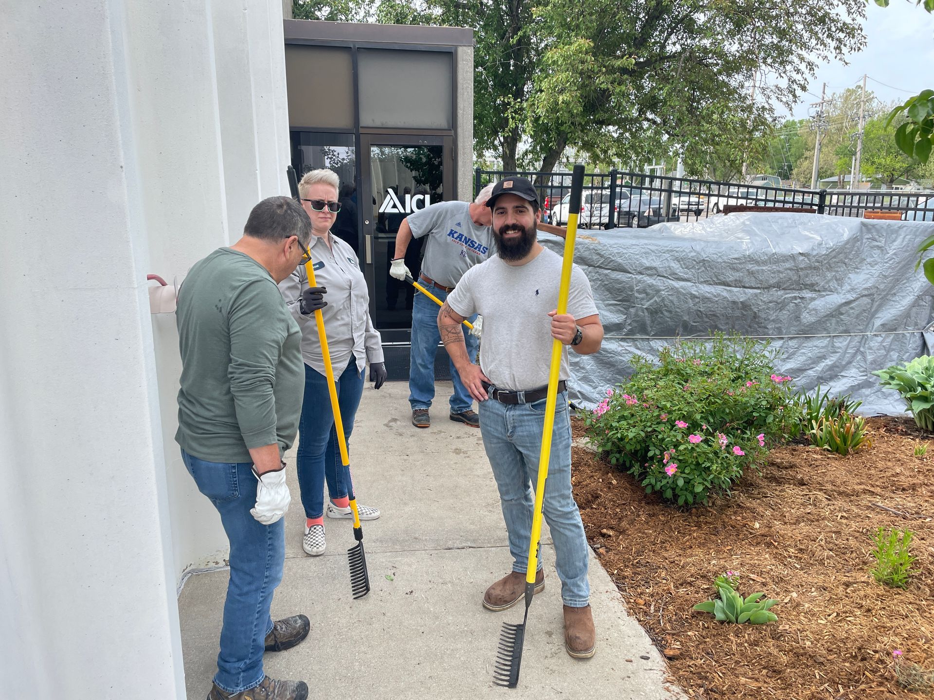 ICL employees are standing with hoes and smiling for the ICL Spring Planting.
