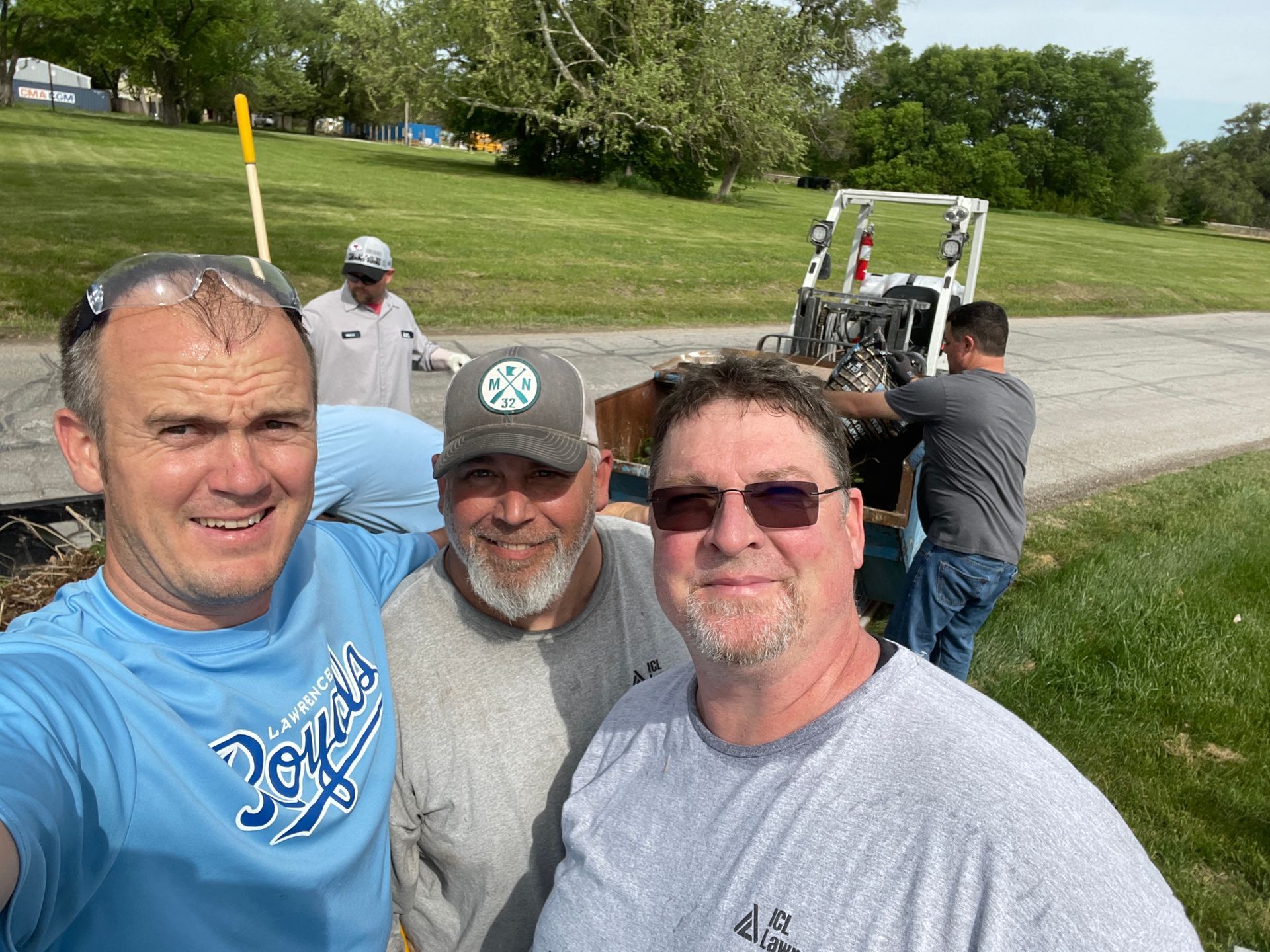 Three men stand and smile at the camera during the ICL Spring planting.