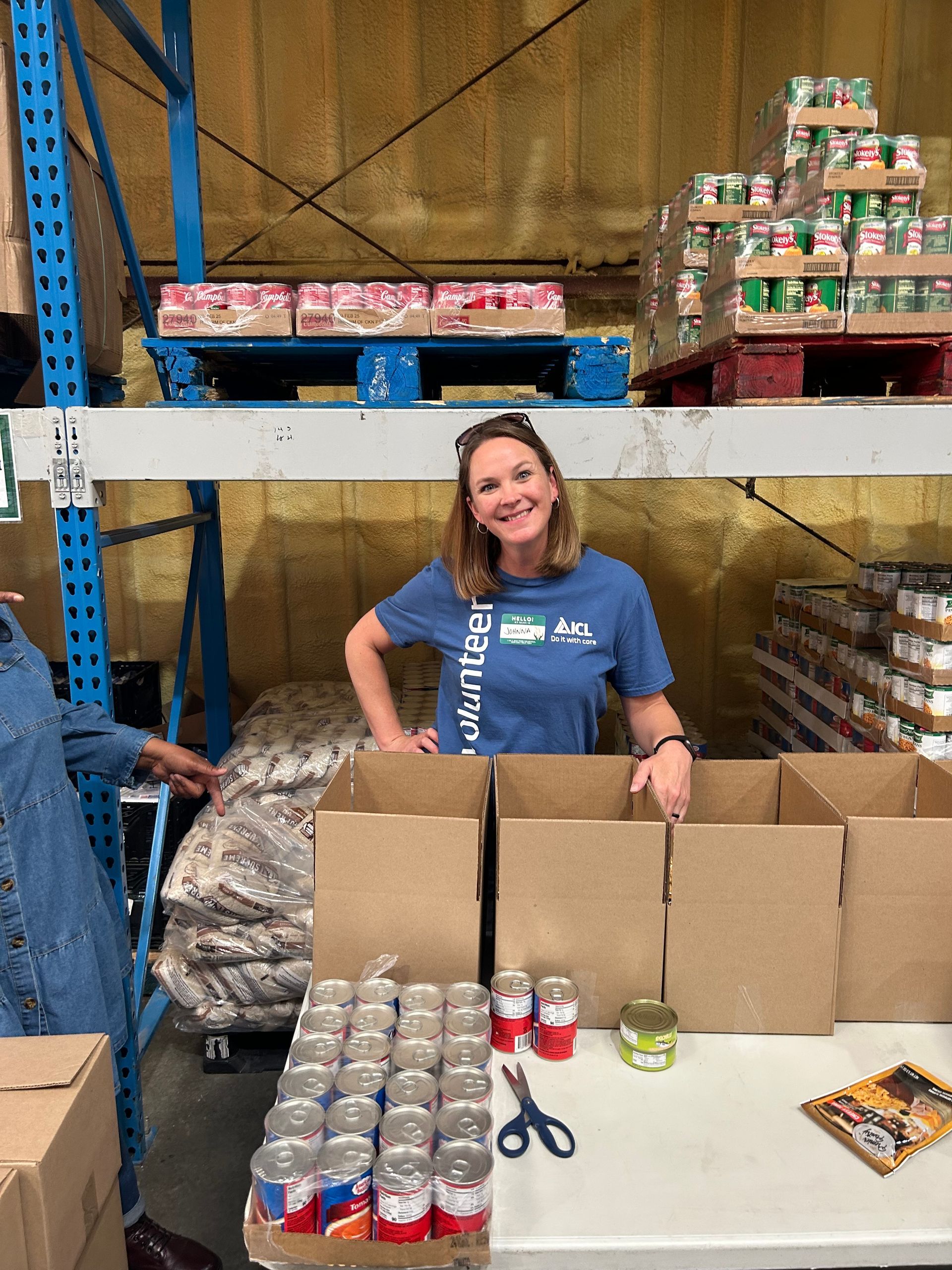 A woman is smiling at the camera for the community food drive.