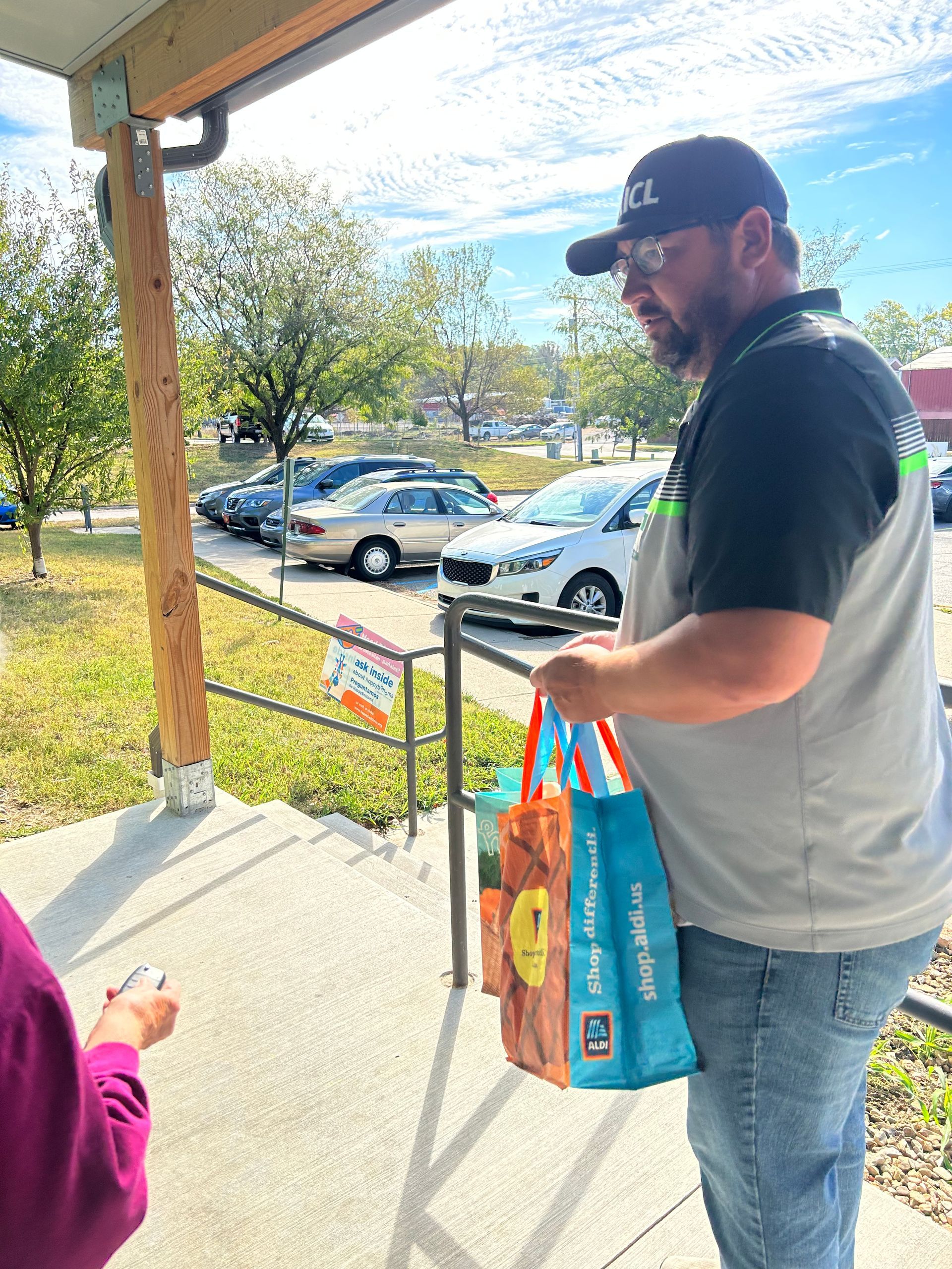 The community food drive volunteer is holding a bag of food.