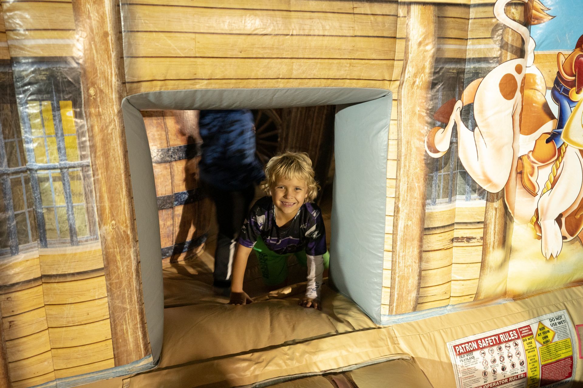 A little boy is playing in a bouncy house.