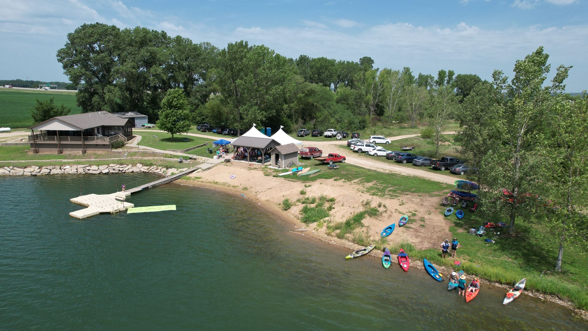 Arial view of the summer picnic with a beach, dock, and two large tents.