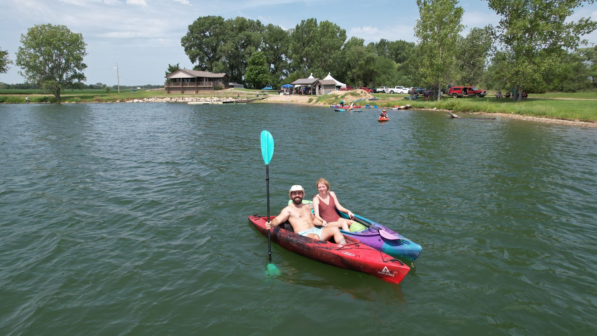 A man and a woman are each in their kayaks and are smiling for the camera.