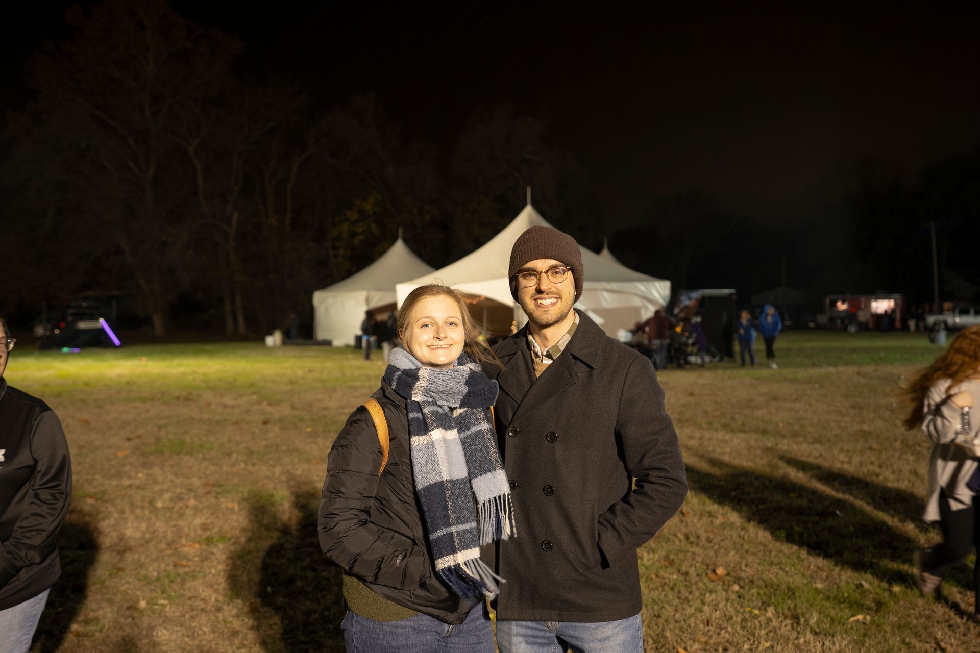 A man and a woman are posing for a picture in a field at night.