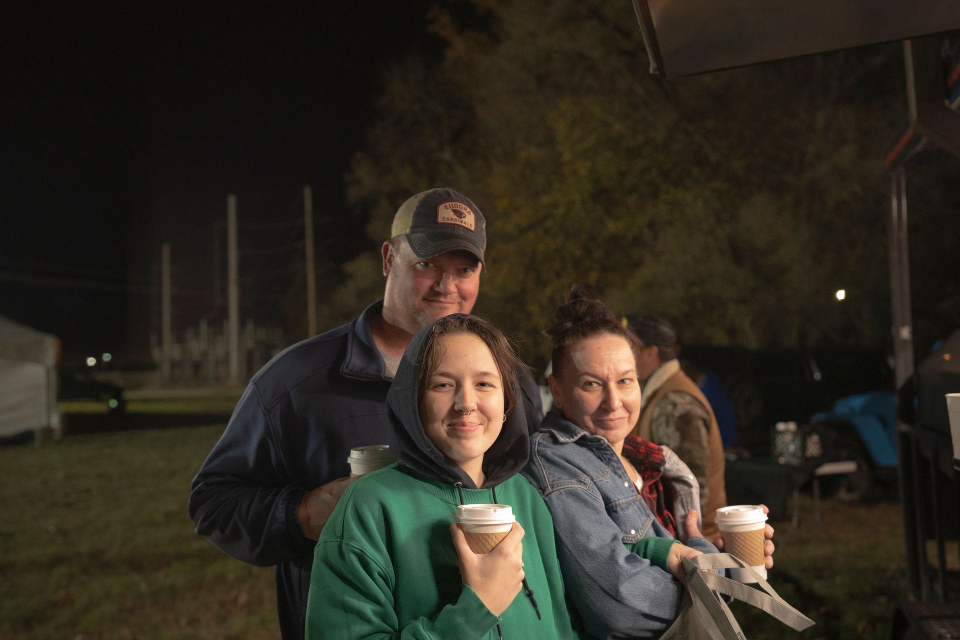 A man and two women are standing next to each other holding cups of coffee.