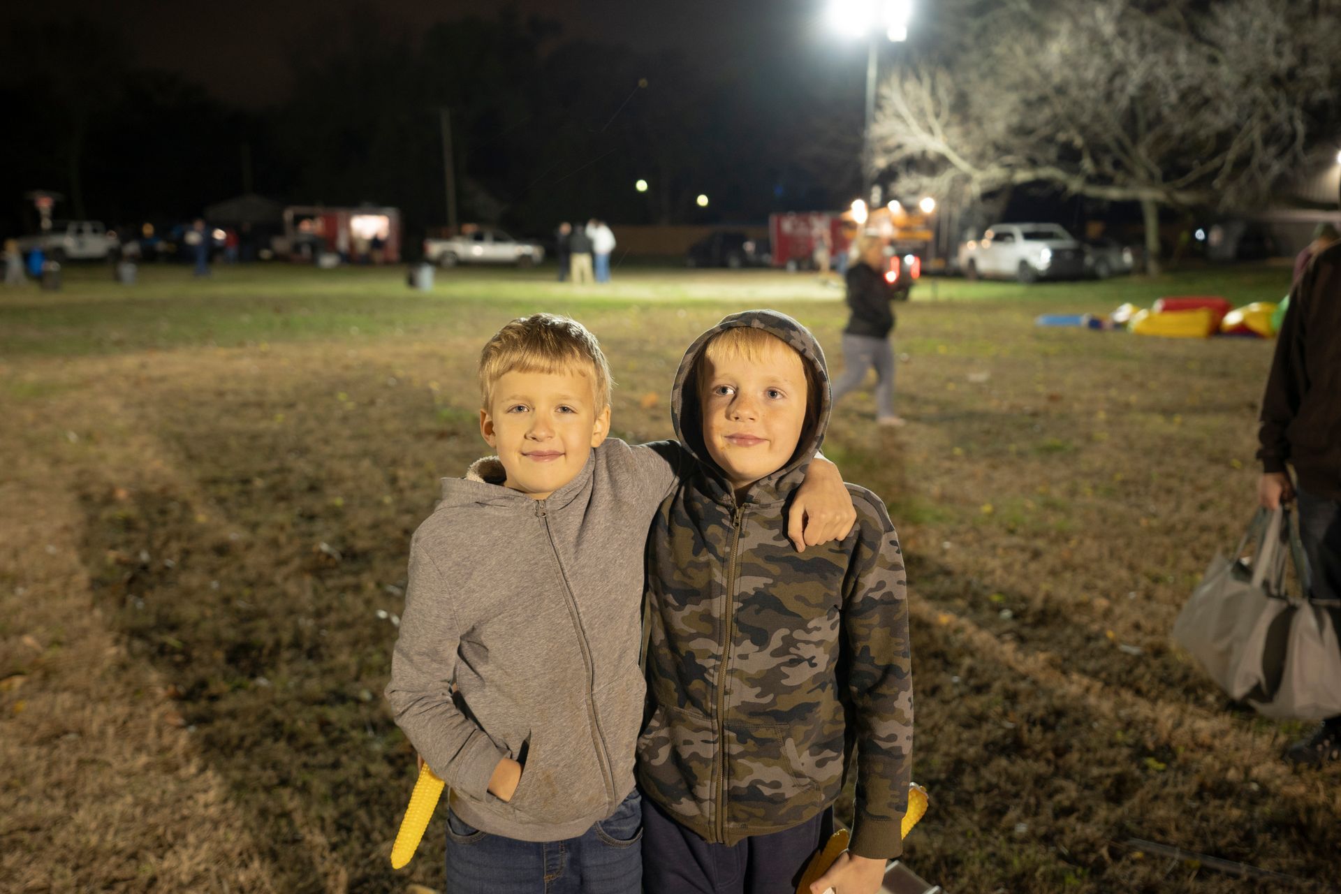 Two young boys are posing for a picture in a field at night.