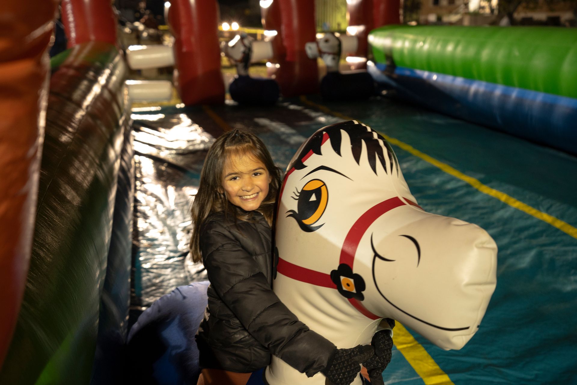 A little girl is riding on the back of an inflatable horse.