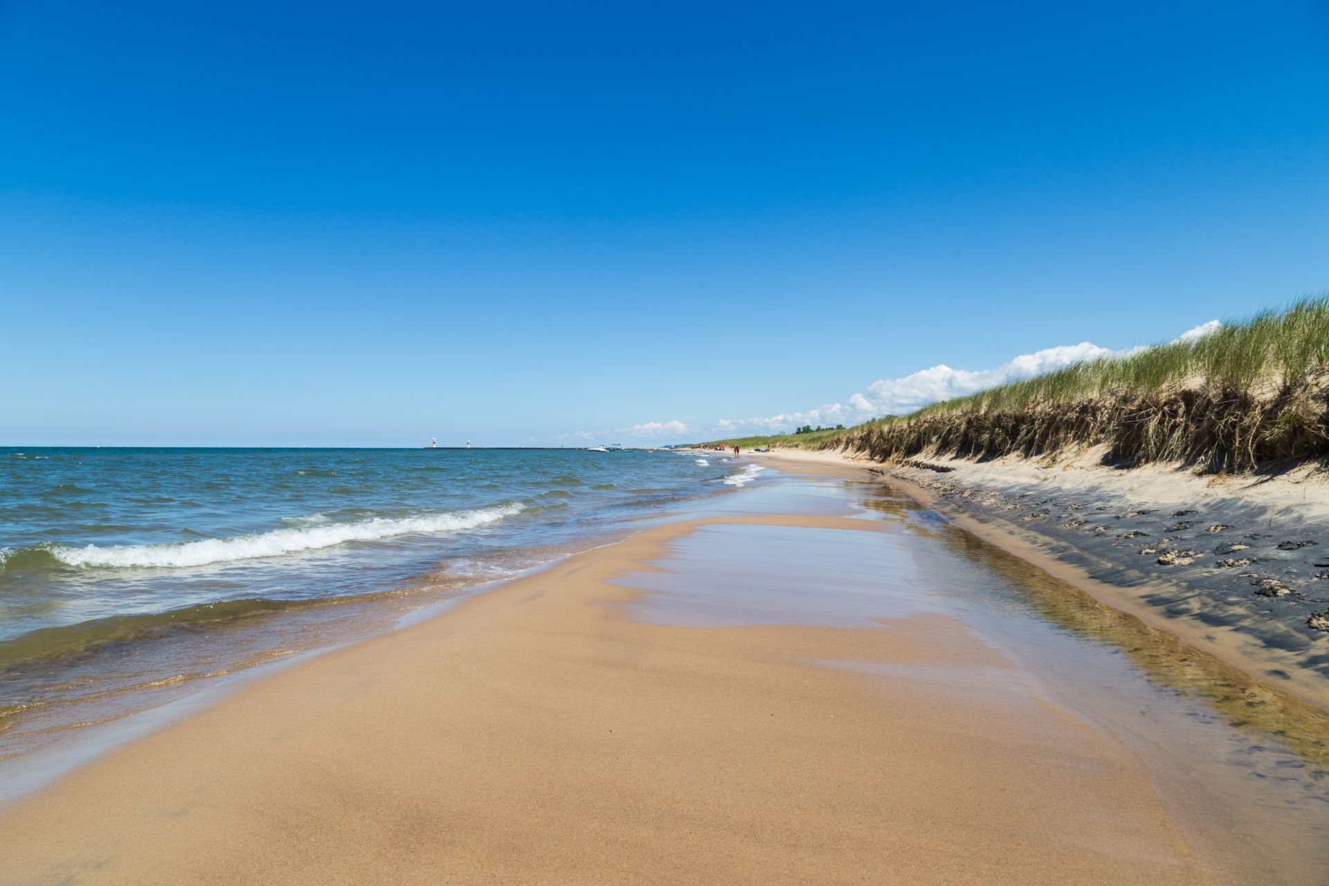 A long sandy beach leading to the ocean on a sunny day.