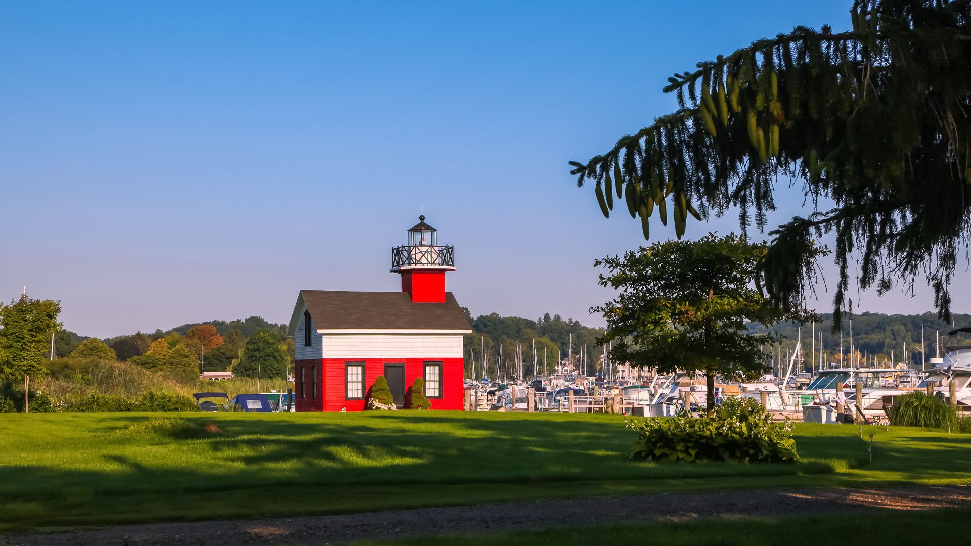 A red and white lighthouse is sitting on top of a lush green field.