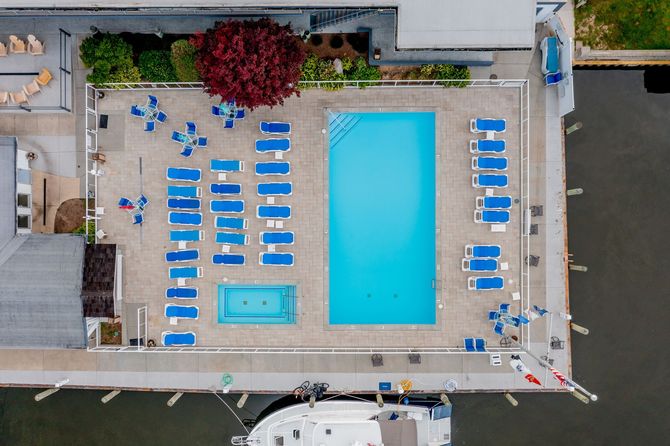 An aerial view of a swimming pool surrounded by chairs and a boat.