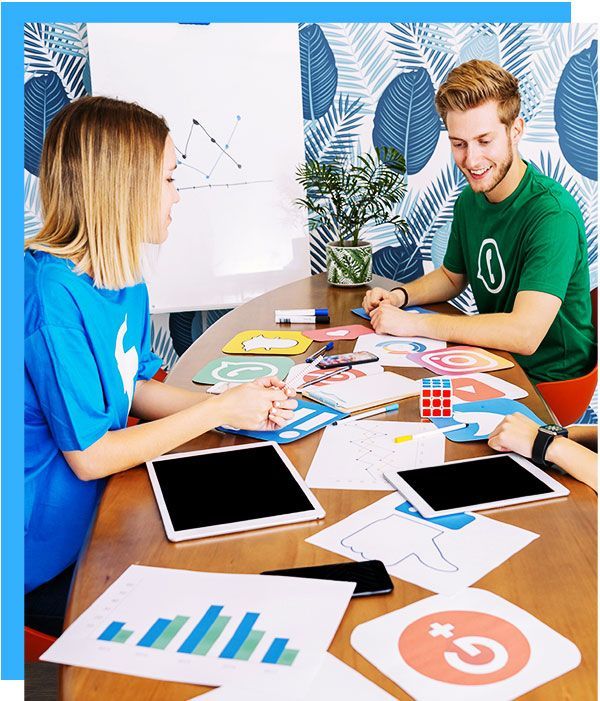 A man and a woman are sitting at a table with papers and tablets.