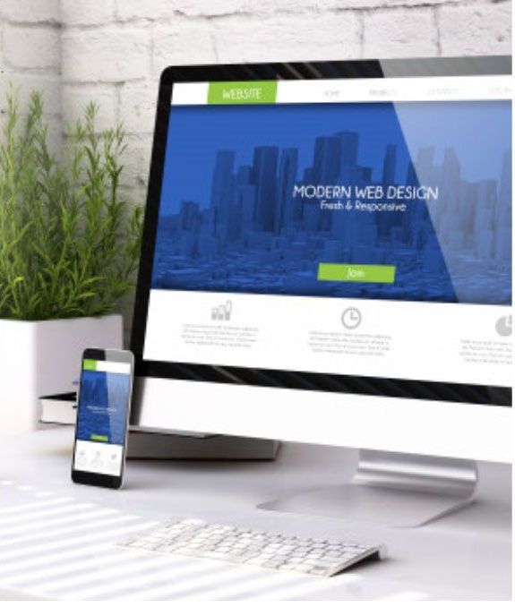 Computer and smartphone displaying modern website design on a white desk, next to a plant.