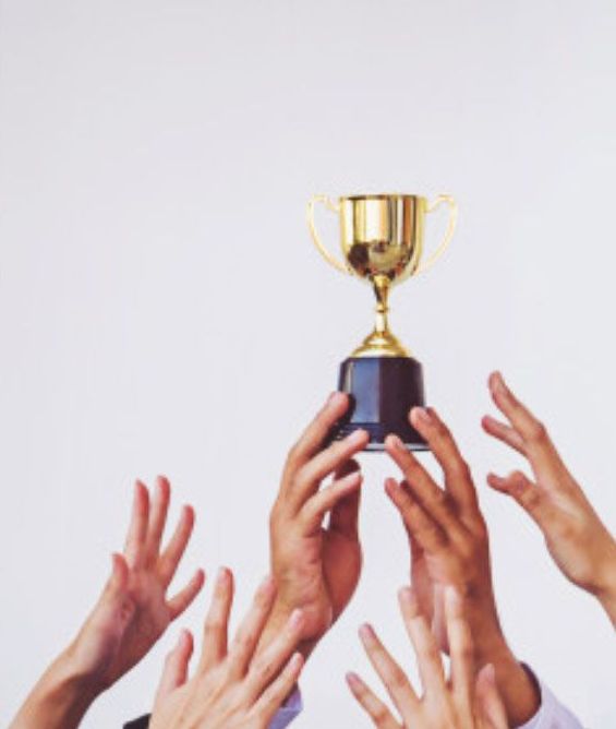 Hands reaching up toward a golden trophy held aloft against a white background, symbolizing achievement and success.