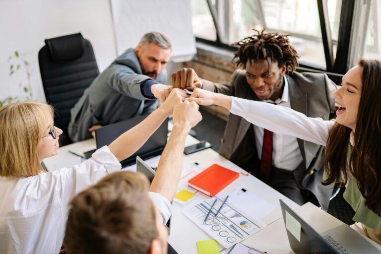 A group of people are giving each other a high five in an office.