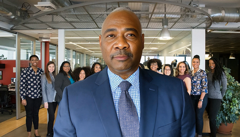 A man in a suit and tie is standing in front of a group of people.