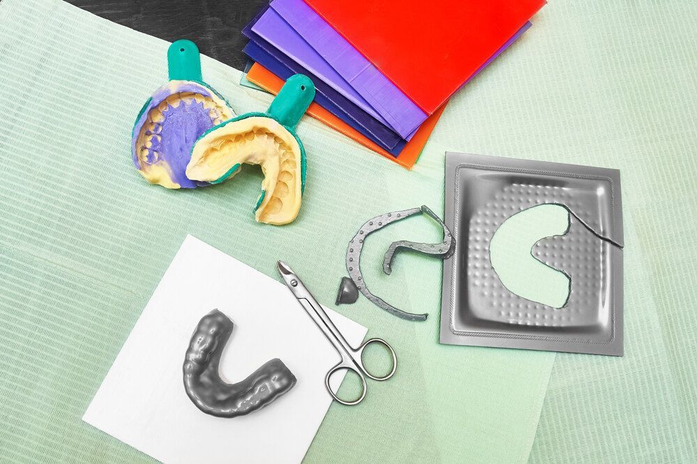 A Dental Tray With A Tooth Impression And A Pair Of Scissors On A Table — Dentures Direct Taree-Rod Hinton In Taree, NSW