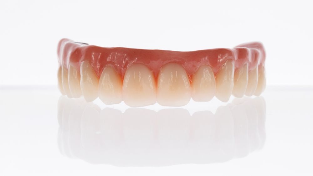 A Close Up Of A Denture On A White Surface — Dentures Direct Taree-Rod Hinton In Laurieton, NSW